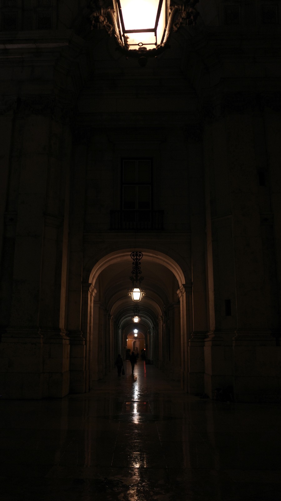 A dark arcade lit by a line of ceiling lights