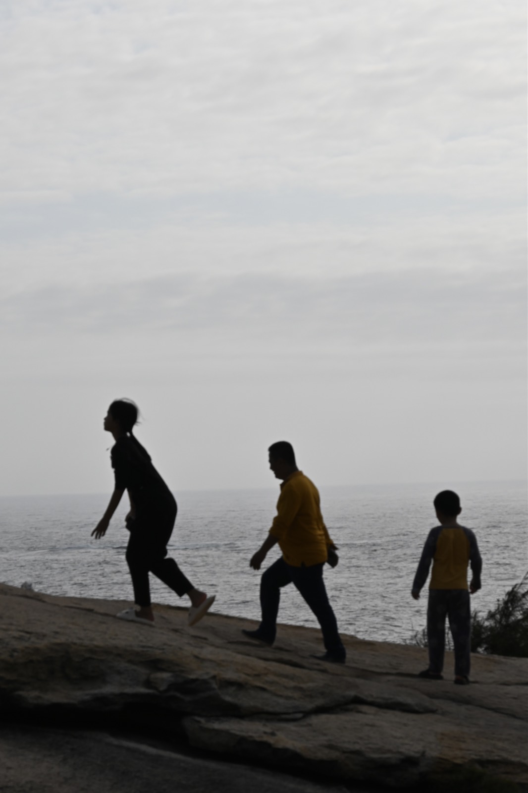 Three silhouetted people standing by the sea